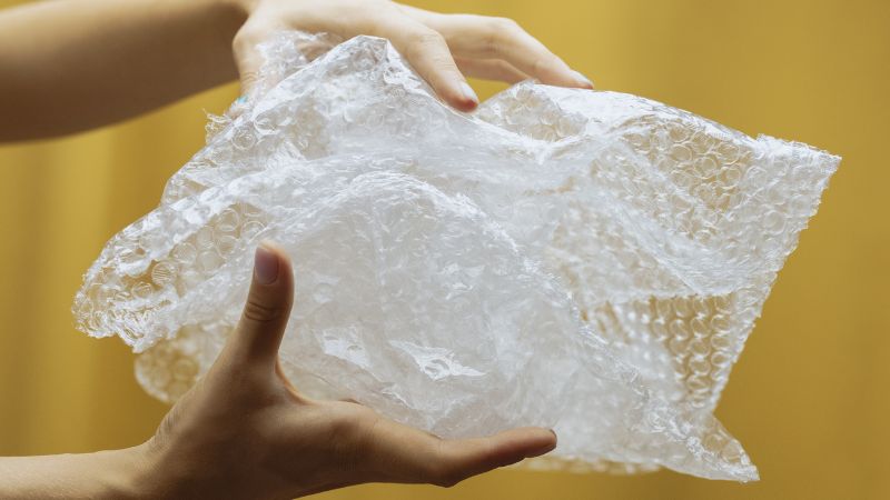 Two hands holding bubble wrap, one method of how to store Christmas tree decorations.