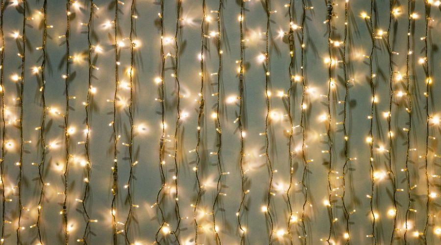 Several strings of fairy lights hanging in a row, which shows how to store Christmas tree decorations properly. 