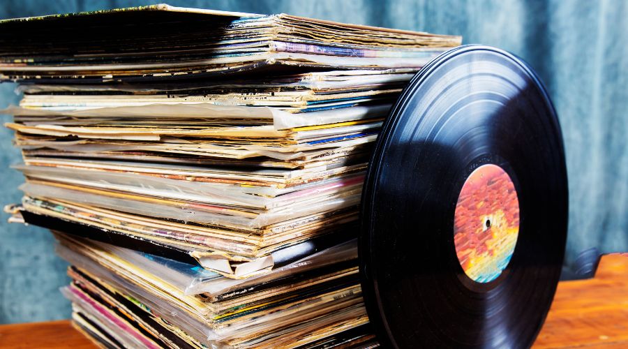 A vinyl record stacked against a collection of record sleeves