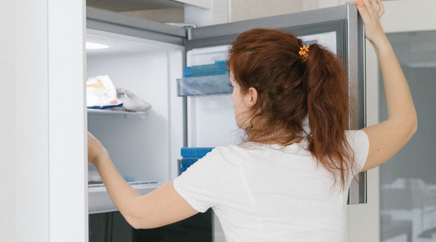 A woman preparing a freezer for storage.