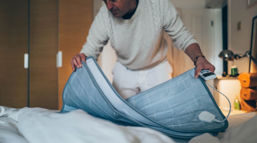 A man packing away an electric blanket to store it when not in use.