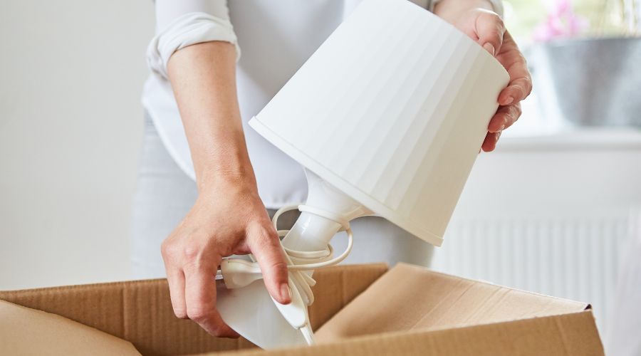 A person unpacking a lamp after moving.